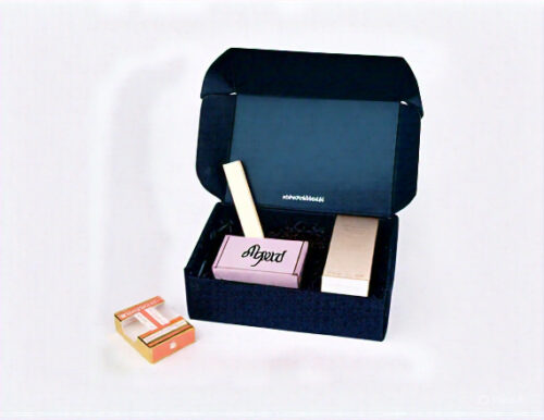 Custom makeup packaging boxes with cosmetic products inside, including branded beauty items neatly placed in a black mailer box