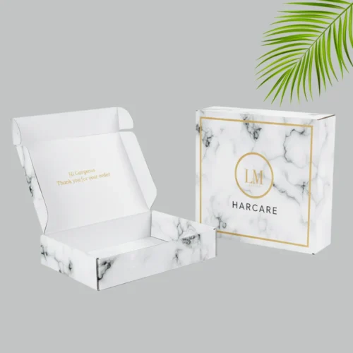 A luxury marble mailer boxes with gold accents. The outer box features the logo in a gold circle design.