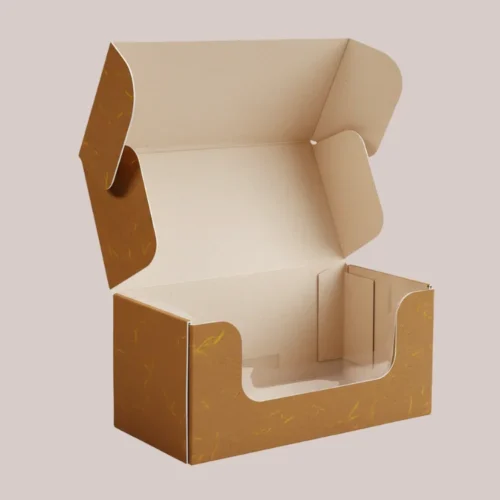 An open brown mailer box with a cutout window on the front, featuring a rustic paper texture with golden flecks, designed for wholesale cookie packaging.