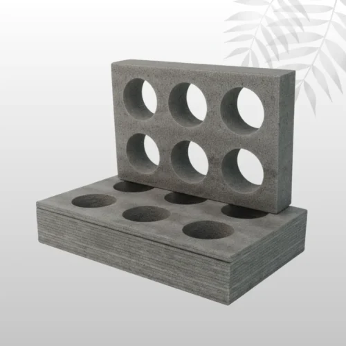 Assortment of two-tone gray and black open-cell packaging foam inserts, showing different depths and custom die-cut product cavities.