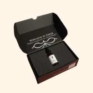 Open black presentation box for 'Canni' CBD oil, showing a single amber dropper bottle nestled securely in a custom black foam insert.